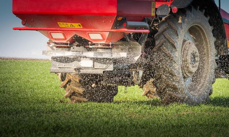 Closeup view of a red tractor applying fertilizer to a field.