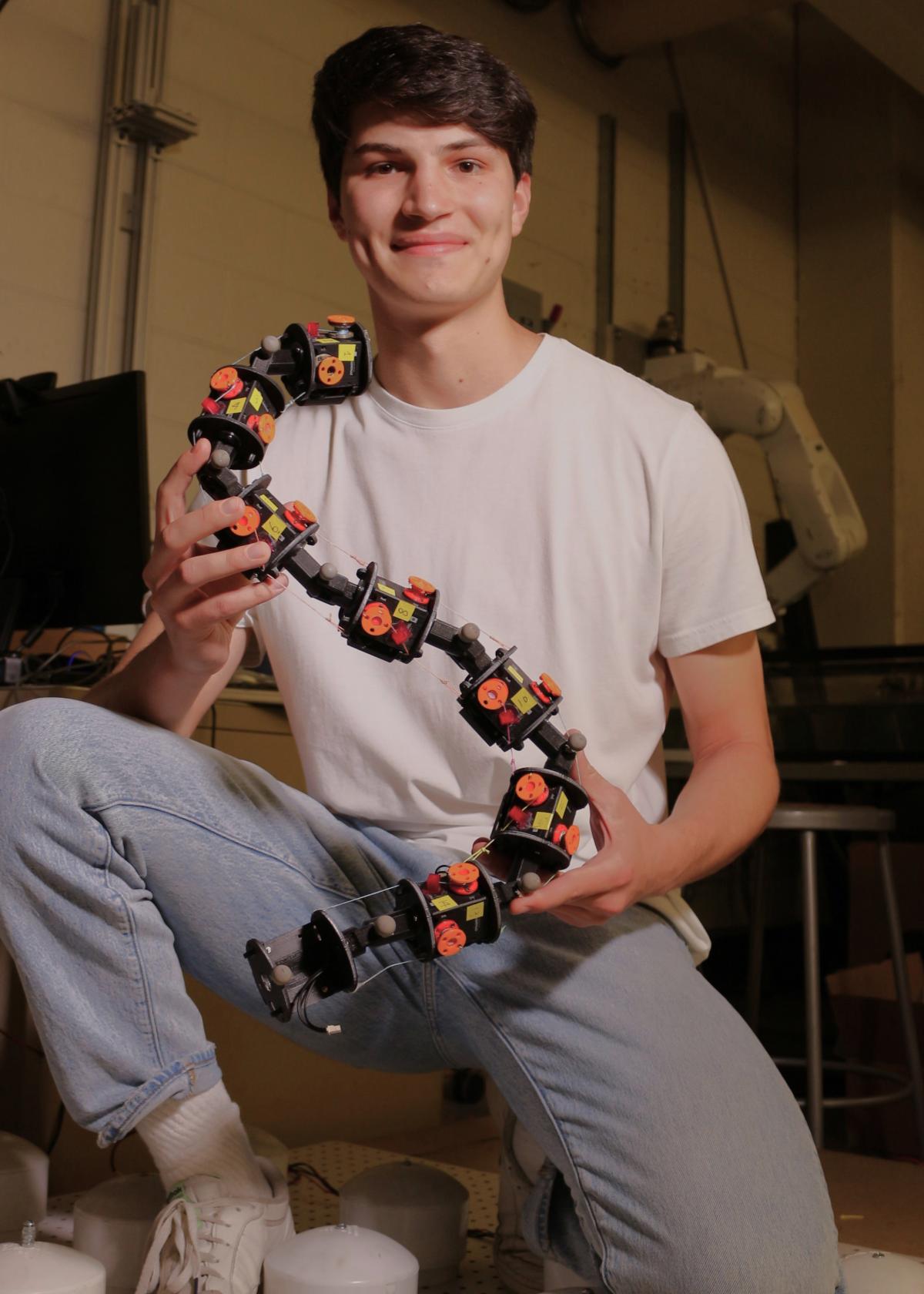 Venny holding his design of a robot inspired by the muscle movements of organisms without limbs