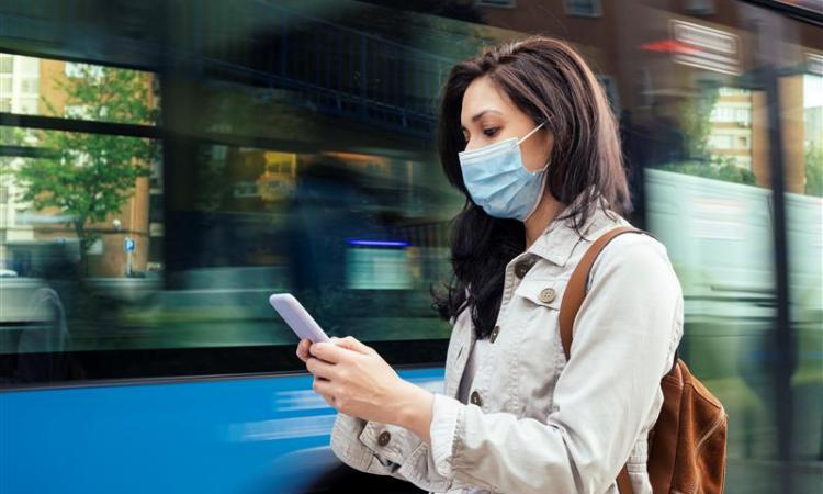 woman on phone next to bus