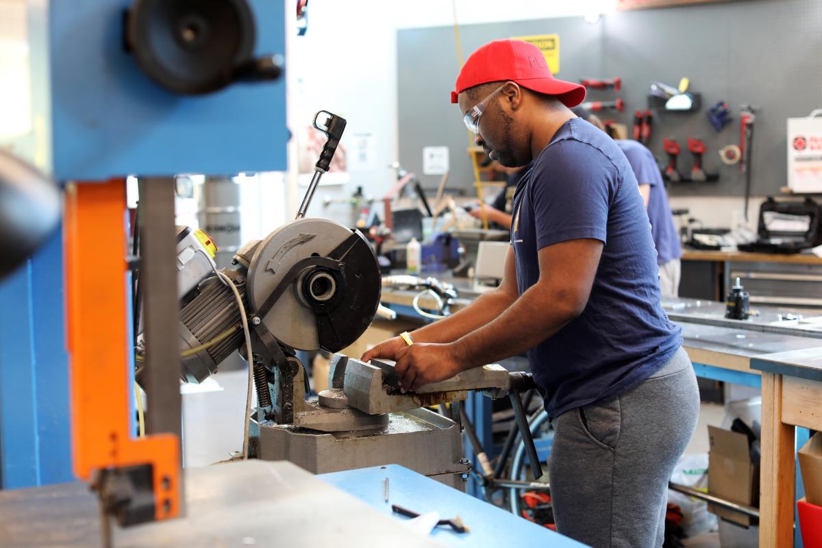 A student uses a saw in the Invention Studio