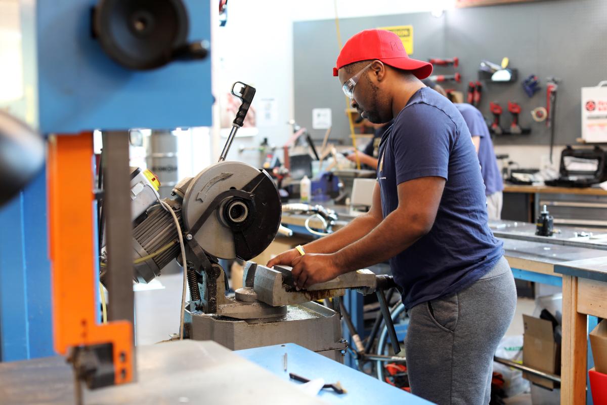 A student uses a saw in the Invention Studio